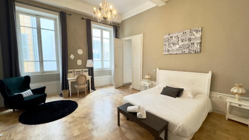a bedroom with a white bed and a chair at Les Suites de Sautet - Chambéry centre in Chambéry