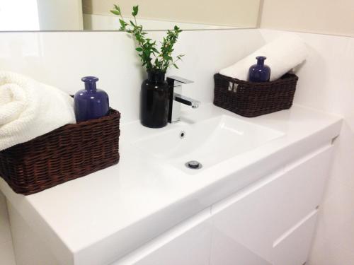 a bathroom sink with two baskets on top of it at Ivy and Roses Boutique Apartments in Canberra