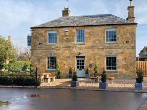 a stone building with picnic tables in front of it at The Seagrave Arms in Weston Subedge