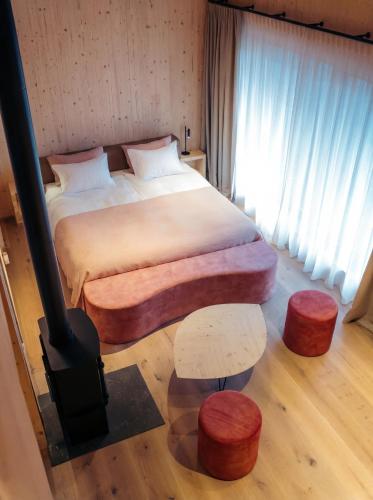 a bedroom with a large bed and two stools at Le Relais D'Orti in Sainte-Ode