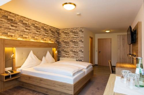 a bedroom with a large bed and a brick wall at Land-gut-Hotel Räuber Lippoldskrug in Alfeld