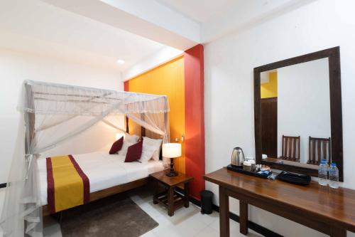 a bedroom with a bed and a desk and a mirror at Urban Kandy City Hotel in Kandy