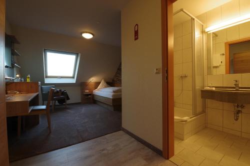a bathroom with a sink and a shower and a bed at Land-gut-Hotel Räuber Lippoldskrug in Alfeld