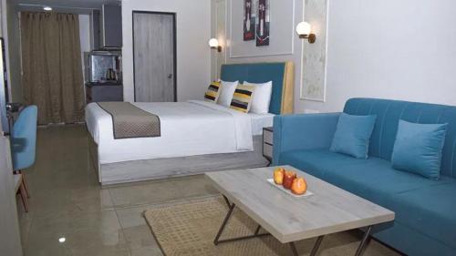a hotel room with a bed and a blue couch at Iconic Studio Apartment in Jaipur in Jaipur