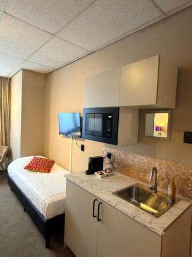 a kitchen with a sink and a bed in a room at Hotel De Stern in Scheveningen