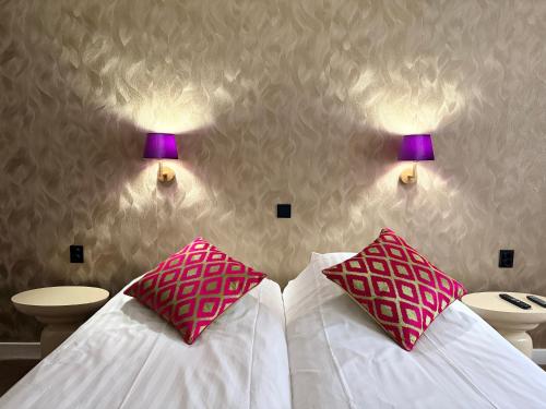 ein Schlafzimmer mit zwei Betten mit rosa Kissen in der Unterkunft Hotel De Stern in Scheveningen