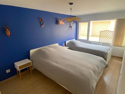 a bedroom with two beds and a blue wall at Charmant appartement et jardin in Saint-Ismier