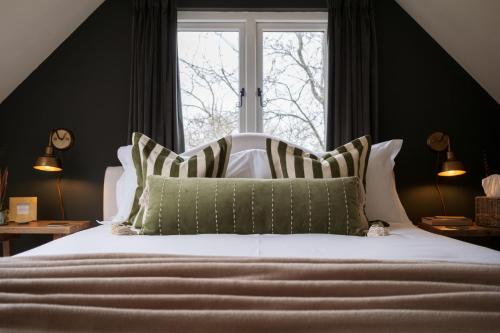a bed with green and white pillows and a window at Roost in Heyshott in Midhurst