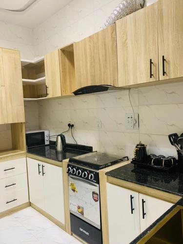 eine Küche mit Holzschränken und einem Herdofen in der Unterkunft ZAPHOMEs in Asaba