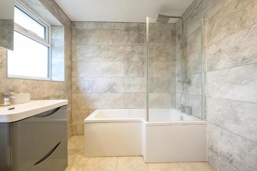 a bathroom with a white tub and a sink at Comfortable 3-BR House in Malvern Link