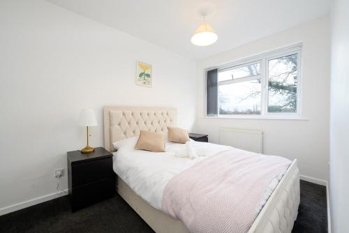 a white bedroom with a large bed and a window at Comfortable 3-BR House in Malvern Link