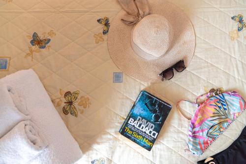 a person wearing a hat and a book on a bed at Kiwi Kastle in Nea Fokea