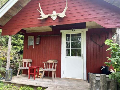 a red house with two chairs and a door at Cozy Off-Grid Cabin - No Power, No Running Water in Skretteberg
