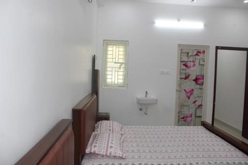 a bedroom with a bed and a window and a sink at Anand Classic in Thiruchendur