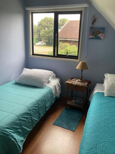 a bedroom with two twin beds and a window at Hospedaje El Roble, Puerto Varas in Puerto Varas