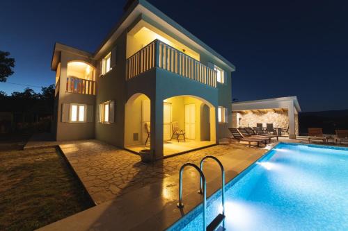 a villa with a swimming pool at night at Villa Green Oasis in Lovreć