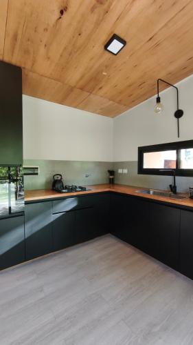 a kitchen with black cabinets and a wooden ceiling at Aire in La Estancia