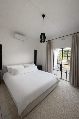 a bedroom with a large white bed and a window at Huis Prins in Prince Albert