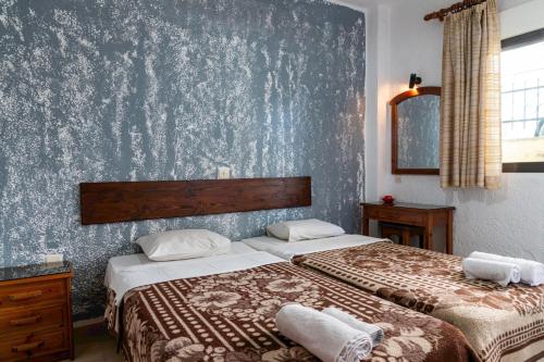 two beds in a bedroom with a blue wall at Kiwi Kastle in Nea Fokea