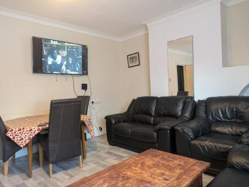 a living room with a leather couch and a table at DACH Apartments - Cozy 3 bed Apartment in Hendon in Colindale
