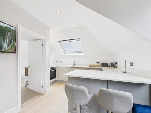 a white kitchen with white counters and white chairs at The loft apartment in Bromley