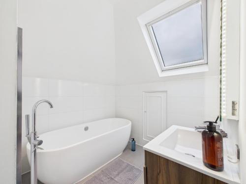 a white bathroom with a bath tub and a window at The loft apartment in Bromley