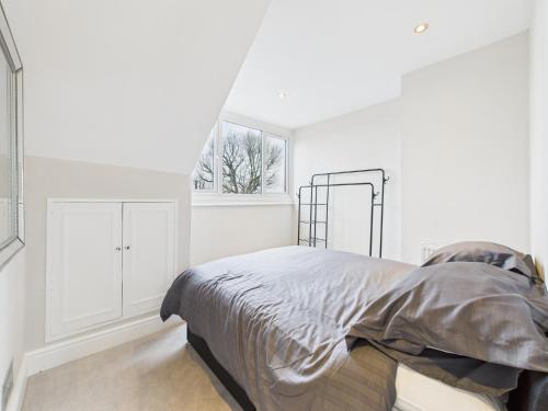 a white bedroom with a bed and a window at The loft apartment in Bromley