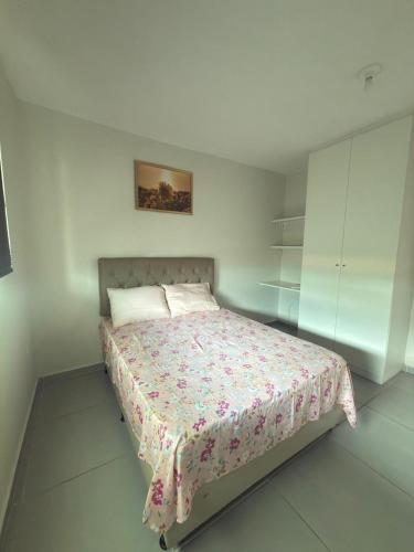 a bedroom with a bed with a floral bedspread at Maragogi Peroba Ville Residence in Maragogi