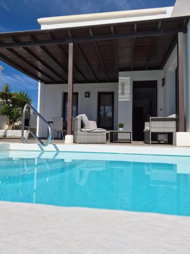 a swimming pool in front of a villa at Casa Sunny in Yaiza