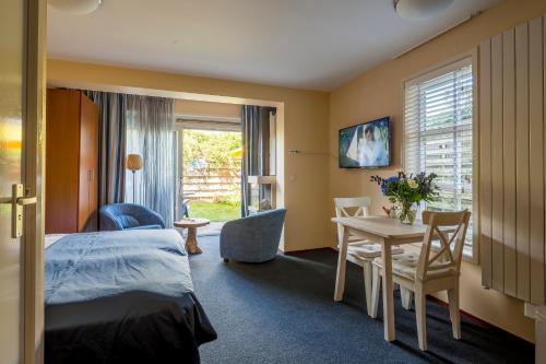 Habitación de hotel con cama, mesa y sillas en Appartementen de Strandloper, en Bergen aan Zee