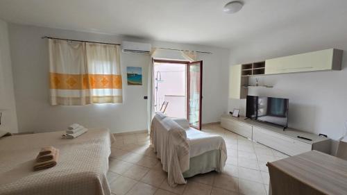 a white room with two beds and a television at Monolocale in centro con parcheggio privato! in Palau