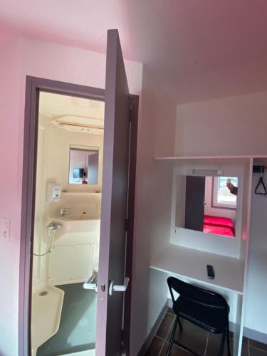 a room with a door and a chair and a mirror at Fast hôtel Troyes in Barberey-Saint-Sulpice