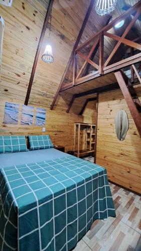a bedroom with a blue bed in a wooden room at Chalé da Ilha in Guaraqueçaba