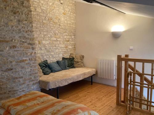 a room with a couch in a brick wall at La maisonnette de la venelle in Chaunay
