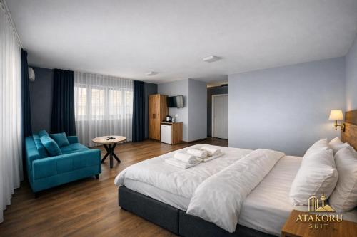 a bedroom with a large bed and a blue chair at ATAKORU Suit in Alacaatlı
