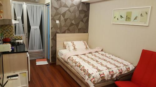 a small bedroom with a bed and a red chair at Papilukas Room Kalibata City - Studio Silver in Jakarta