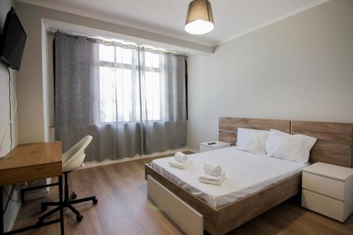 a bedroom with a bed and a desk and a window at QUANICE - Relaxing Guest House in Faro in Faro