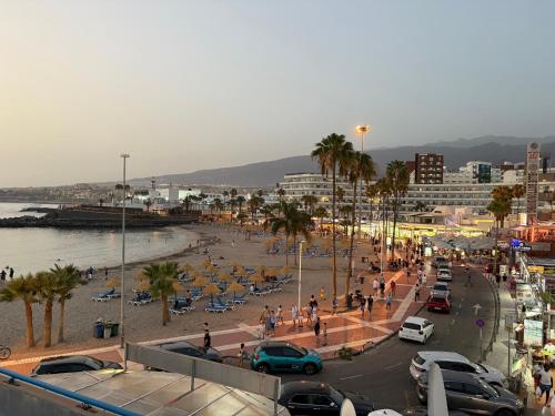 a beach with people and palm trees and cars at Hidden treasure in Playa de las Americas