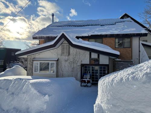 a house covered in snow with a pile of snow at Guest House Tomo in Nosakada