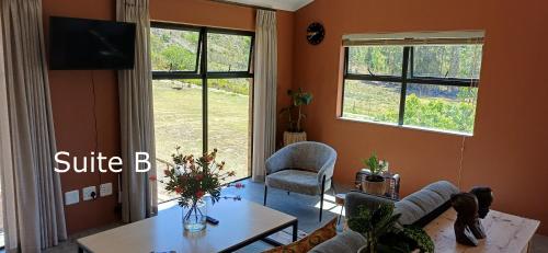 a living room with a table and two windows at Cape Dutch Stay, Suite B in Sedgefield