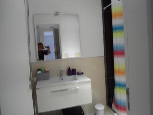 un homme prenant une photo d'une salle de bains avec un miroir dans l'établissement Bay View Apartment Albufeira, à Albufeira