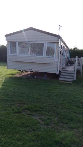a tiny house with a porch and stairs in a yard at Happy Havan in Great Yarmouth