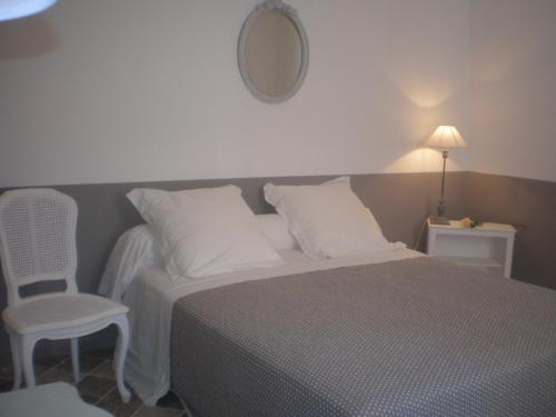 Combas的住宿－La Maison de Papé，一间卧室配有一张床、一把椅子和镜子