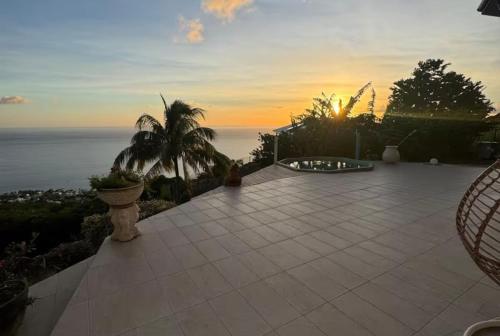a patio with a view of the ocean at sunset at Bas de Villa Tropical Soul in Pointe-Noire