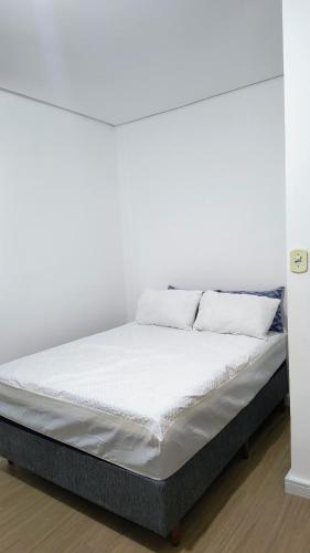a bed with white sheets and pillows on it at Flat Equipado no Centro - Conforto in Governador Valadares