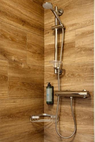 a shower in a bathroom with a wooden wall at Derrynane Bay House in Caherdaniel