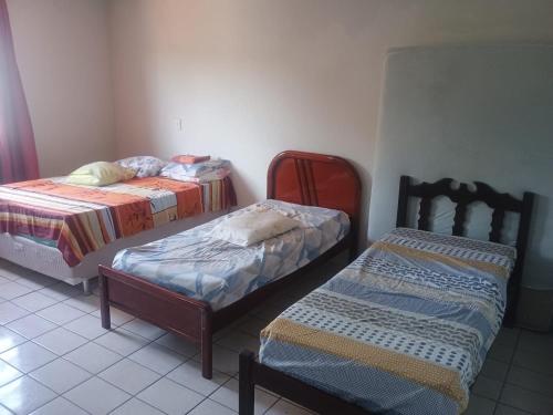a room with two beds and a chair in it at Casa da Vovó Ivete in Guarapari