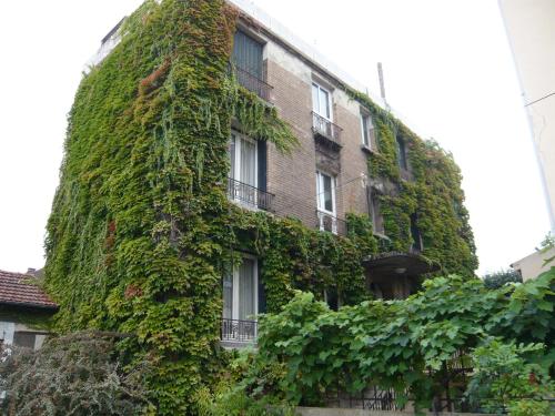 a building covered in ivy in front of a building at Cit'Hotel Aéro-Hotel in Le Blanc-Mesnil