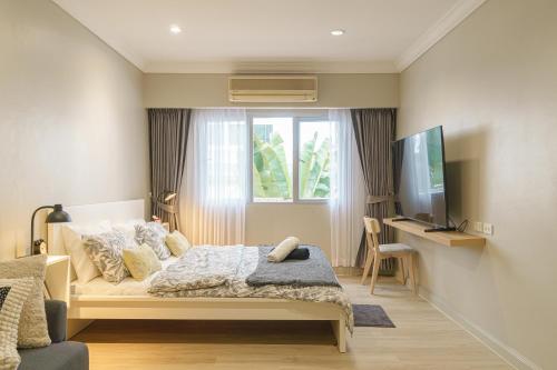 a bedroom with a bed and a tv and a window at Casa Amor in Bang Rak