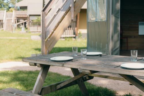a wooden picnic table with plates and glasses on it at Vakantiepark Sallandshoeve in Nieuw-Heeten